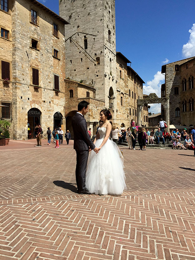 כמה רומנטי, חתן וכלה מצטלמים בכיכר העיירה San Gimignano שהיא ללא ספק מהעיירות היפות ביותר בטוסקנה